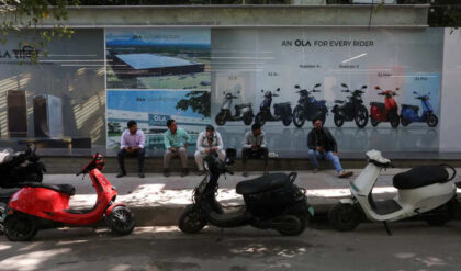 Customers sit outside an Ola service centre with their electric scooters while waiting for servicing in Bengaluru, India.