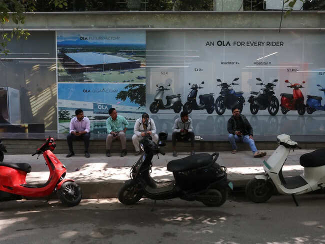 Customers sit outside an Ola service centre with their electric scooters while waiting for servicing in Bengaluru, India.